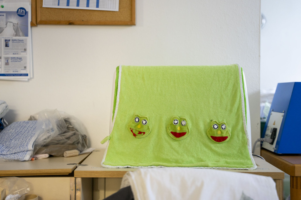 grüne nähmaschinen-abdeckung aus stoff mit aufgestickten Fröschen